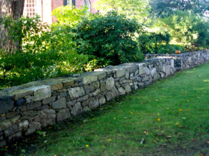 A natural rock wall frames a lawn